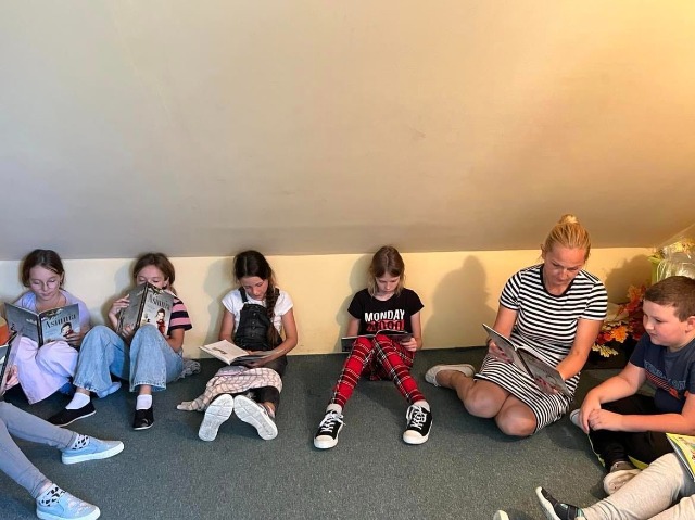 Dzieci siedzące na podłodze czytające książkę