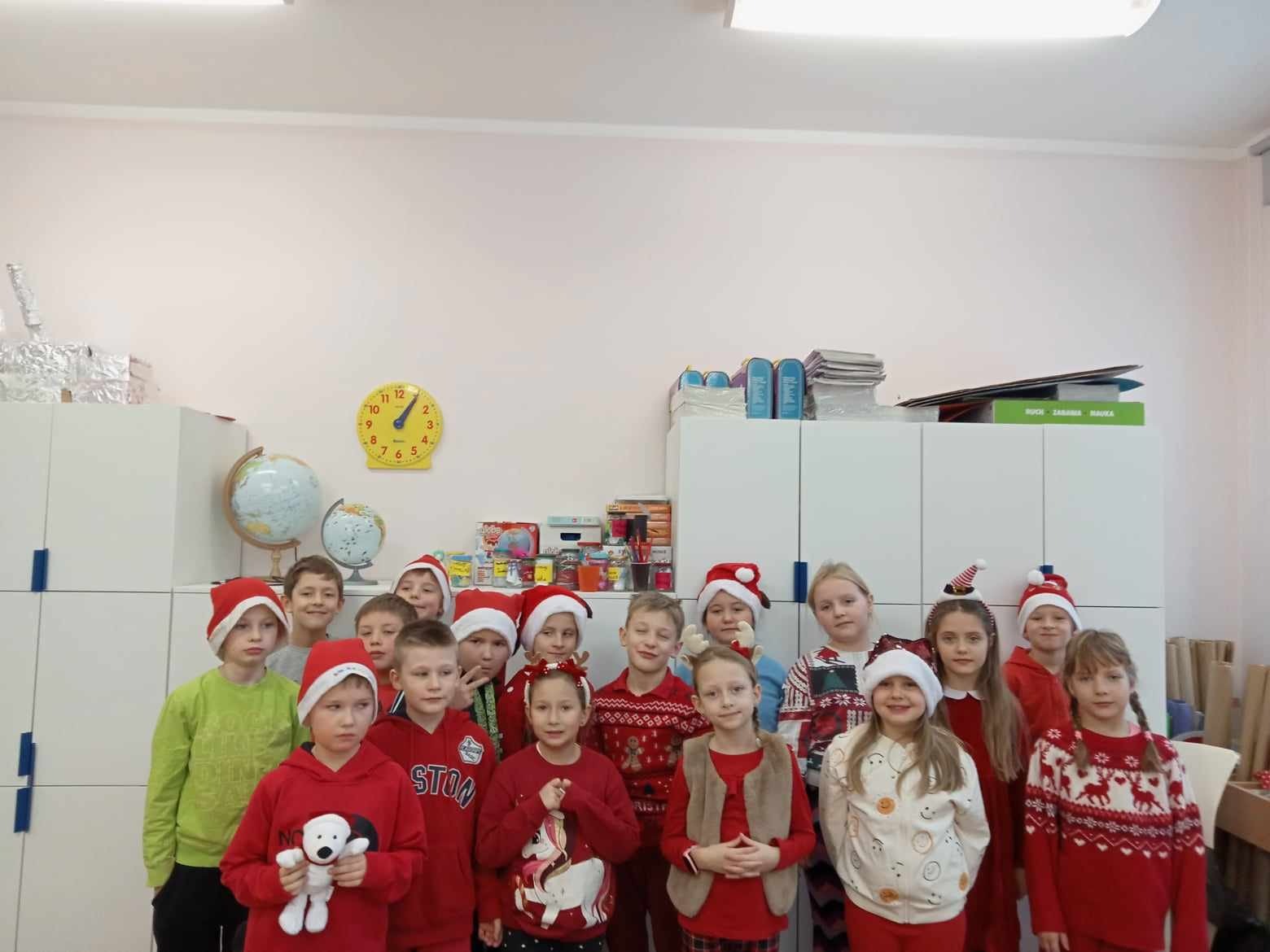 Uczniowie Szkoły Podstawowej Nr 2 im. Mikołaja Kopernika w Olecku w kolorach czerwonych Świętego Mikołaja