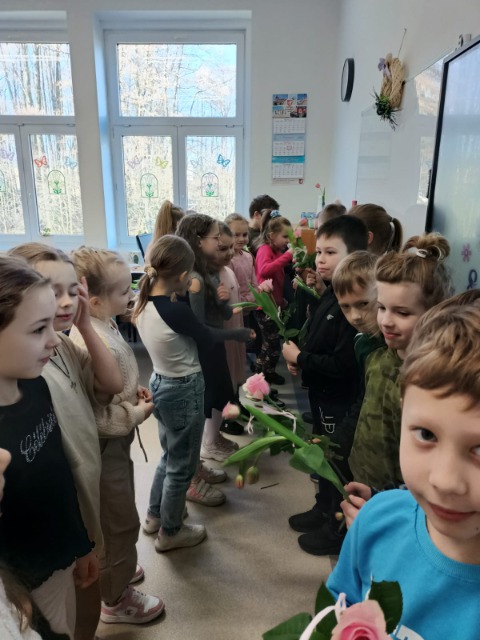 Uczniowie i uczennice z kwiatami.