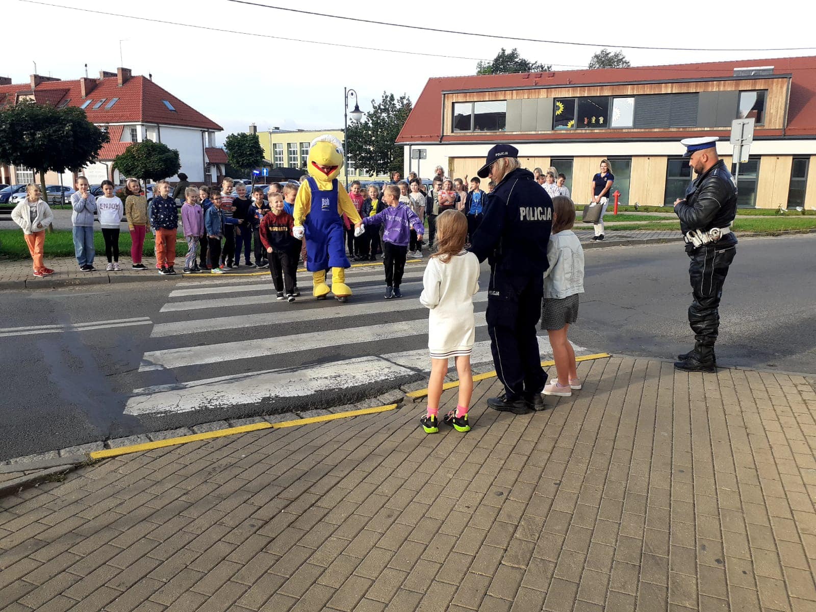 Policjantka uczy dzieci przechodzić przez ulicę.