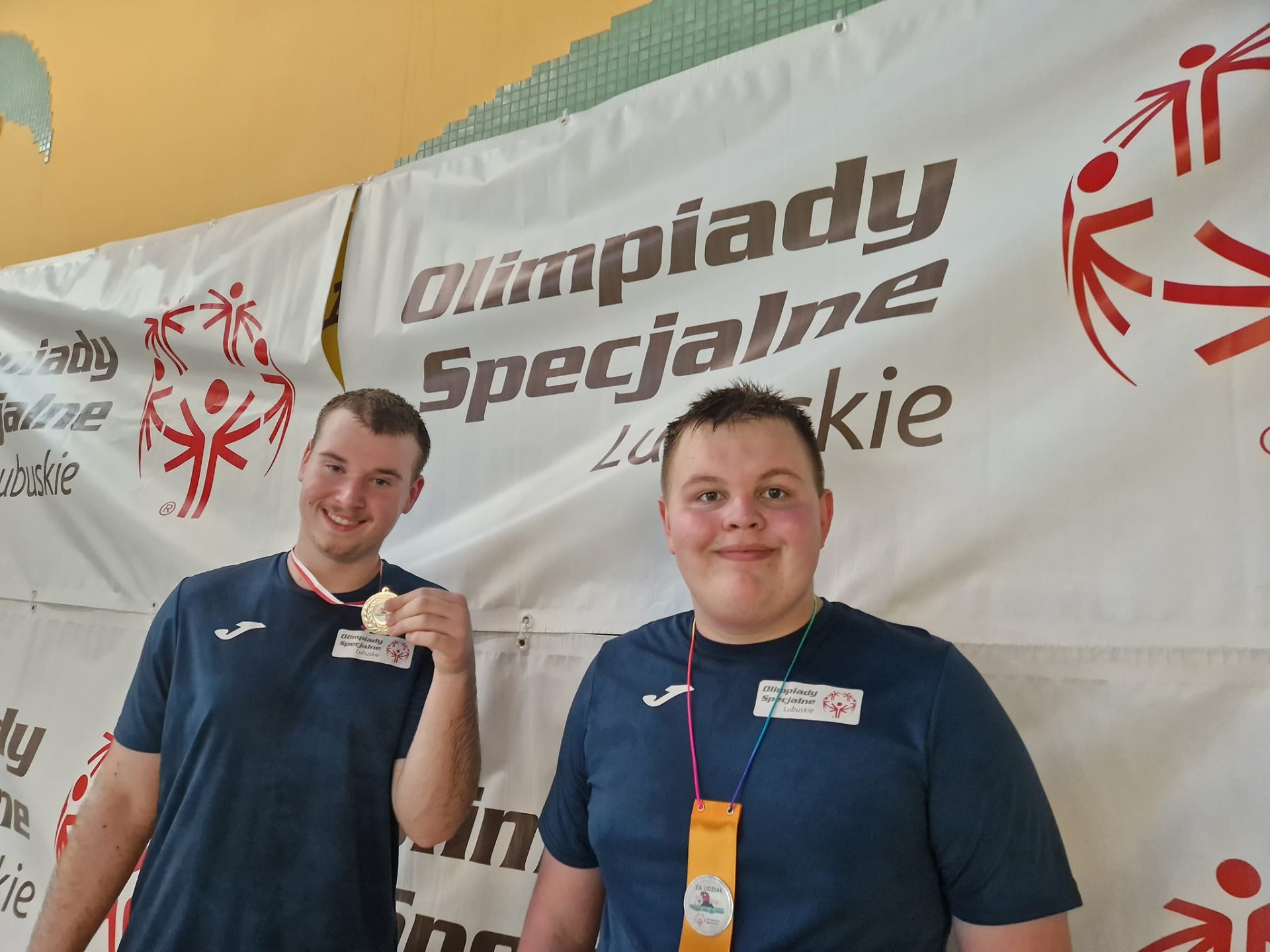 2 uczniów w niebieskich koszulkach z dumą prezentuje medale