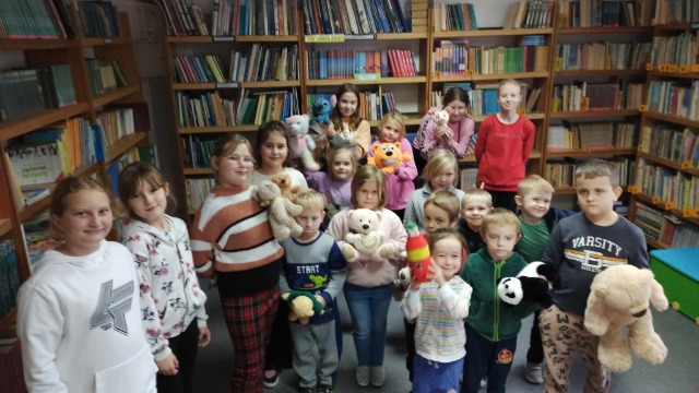 Uczniowie z misiami podczas zabaw w bibliotece z okazji Dnia Misia