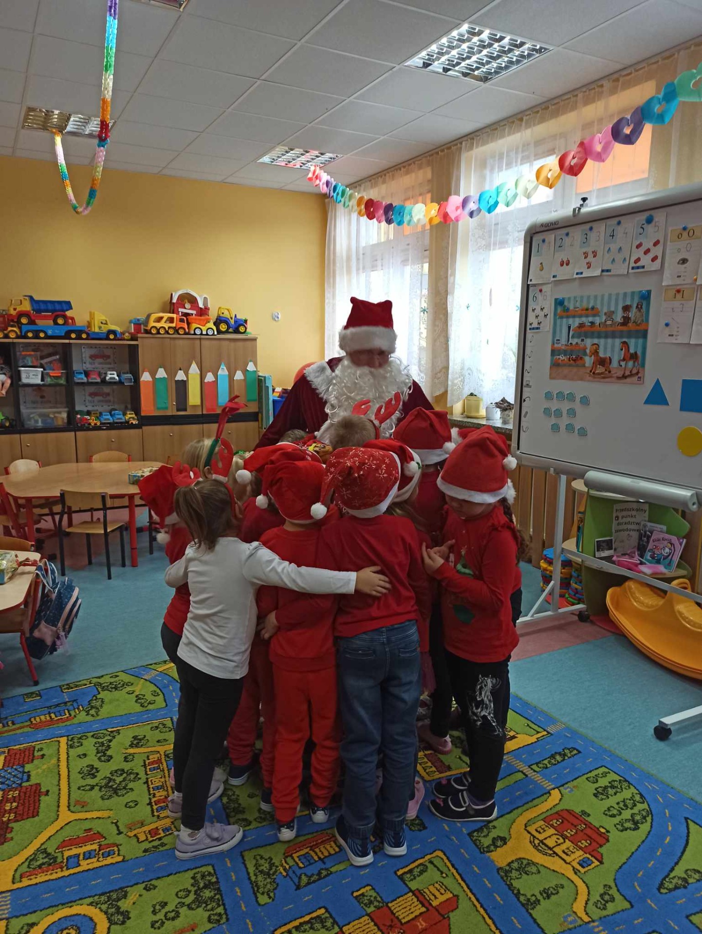 Grupa przedszkolaków wraz z Mikołajem w sali lekcyjnej