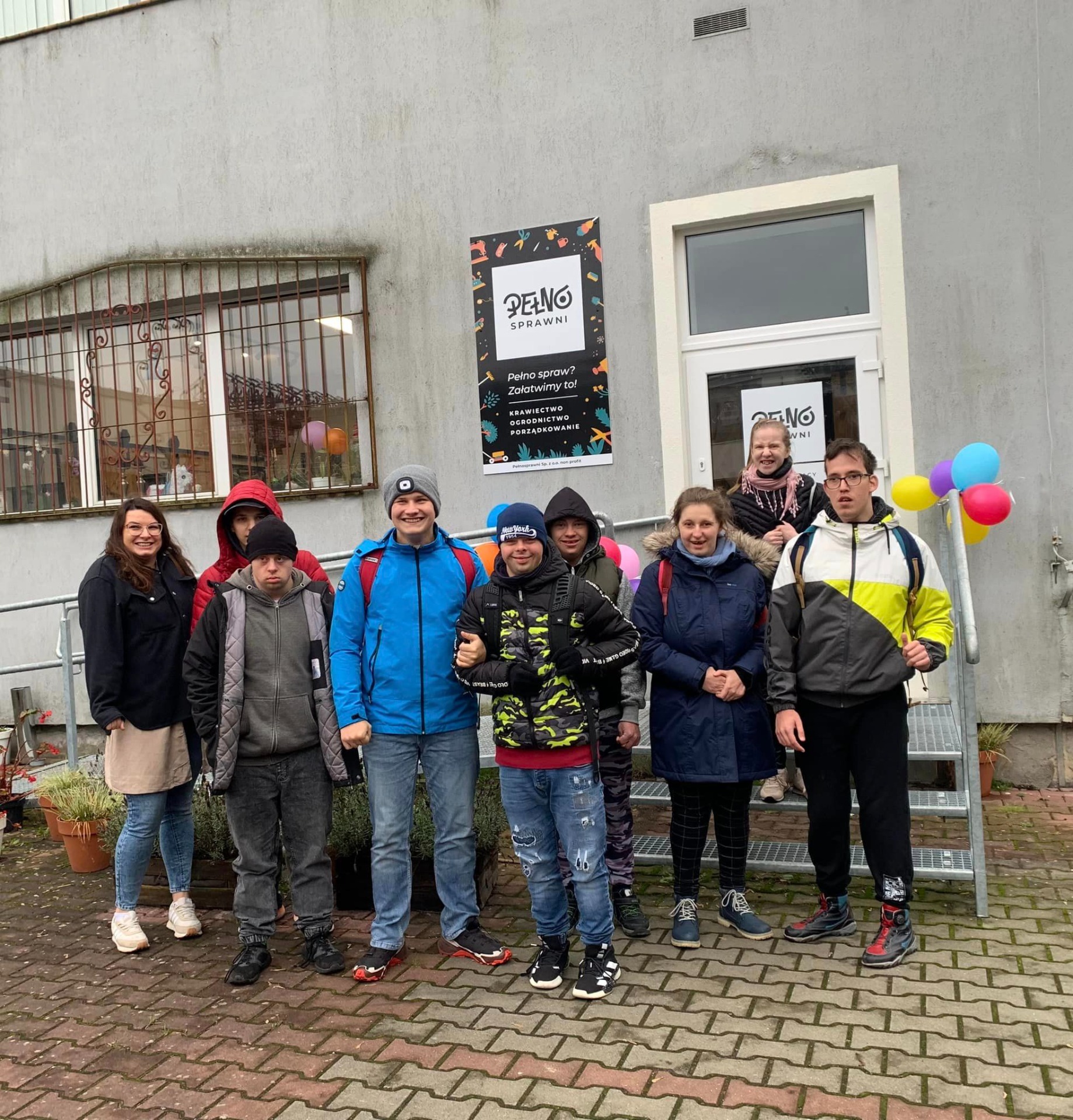 Uczniowie Szkoły Przysposabiającej do Pracy wraz z pomysłodawczynią projektu Panią Emilią przed siedzibą "Pełnosprawnych".