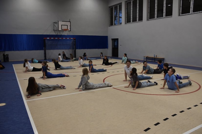 Uczniowie ćwiczą układy taneczne na sali gimnastycznej